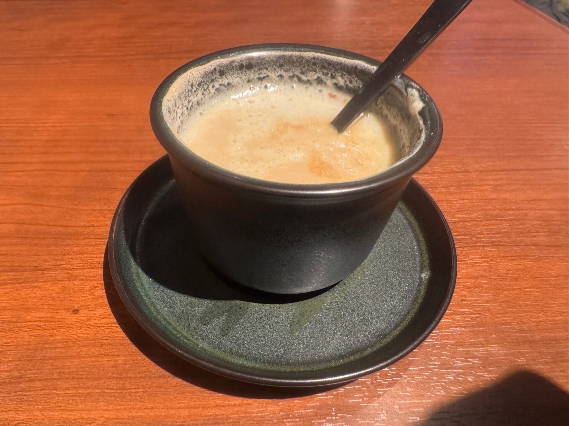 冷めたコーヒーの写真。トッピングのカツオブシは沈んでいるし、ミルクコーヒーにしか見えません