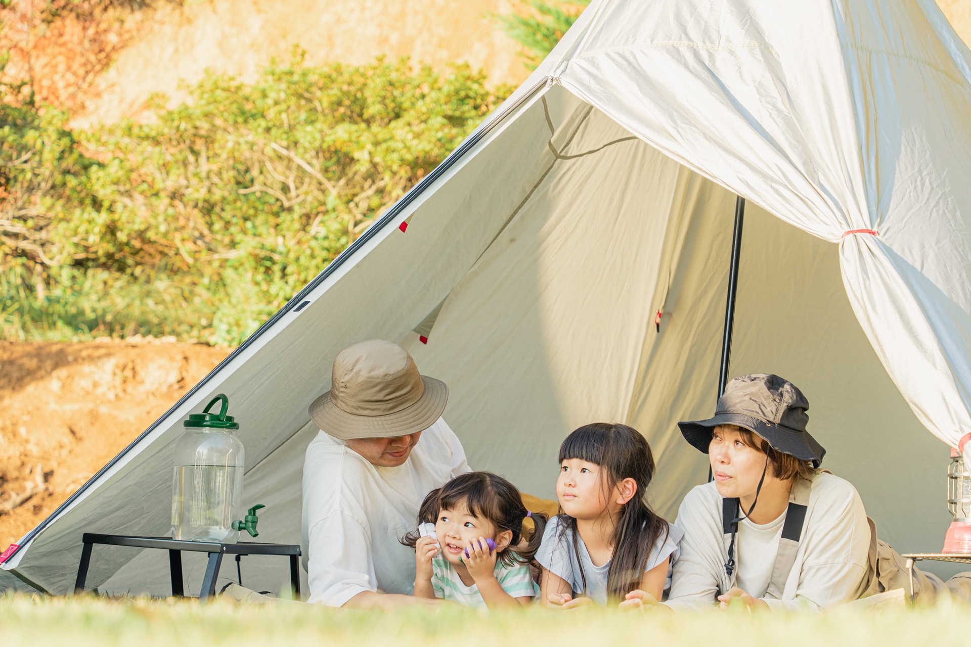 テントの中でキャンプを楽しむ家族の写真