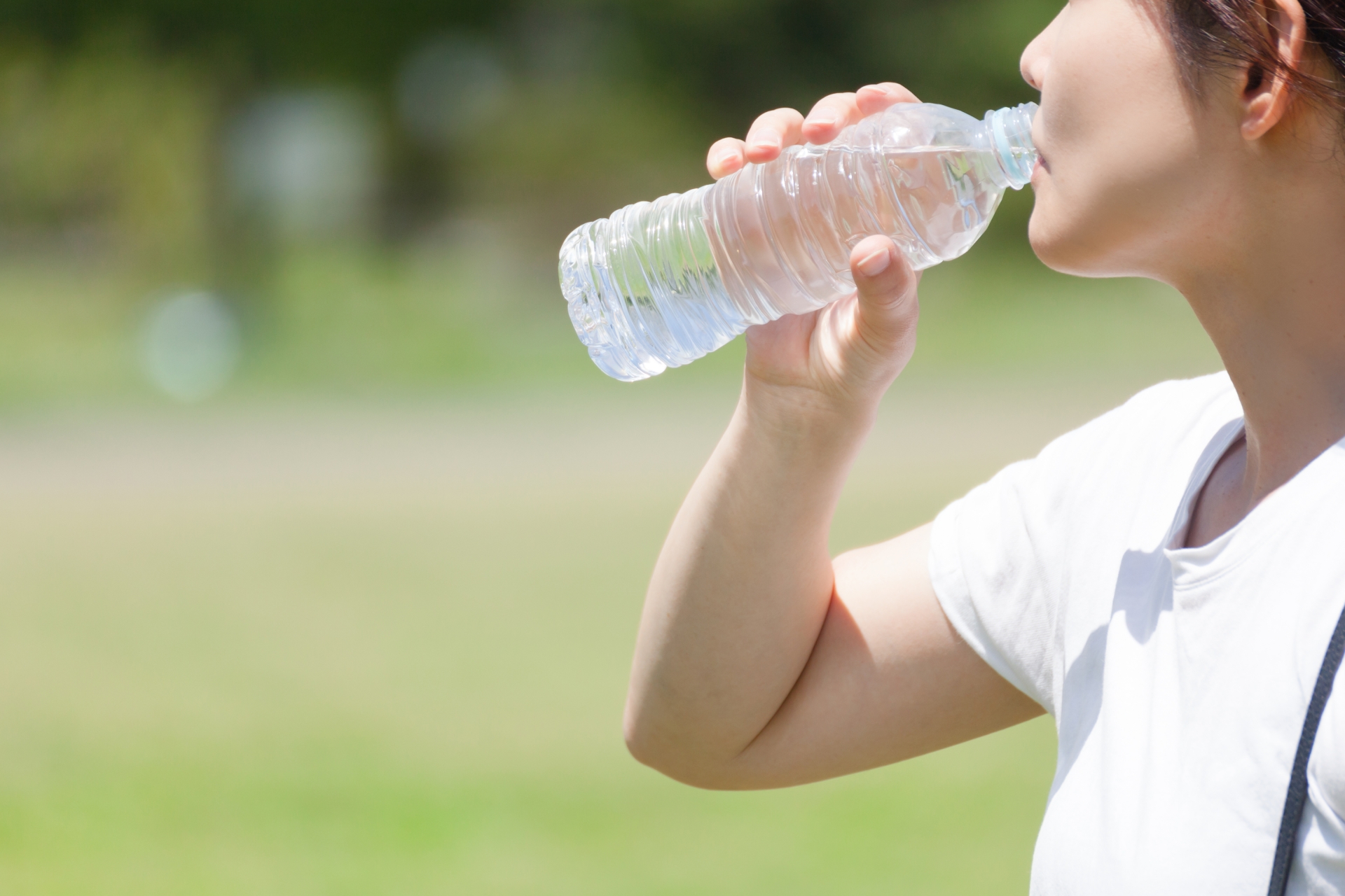 水分補給をするため、ペットボトルの水を飲む女性