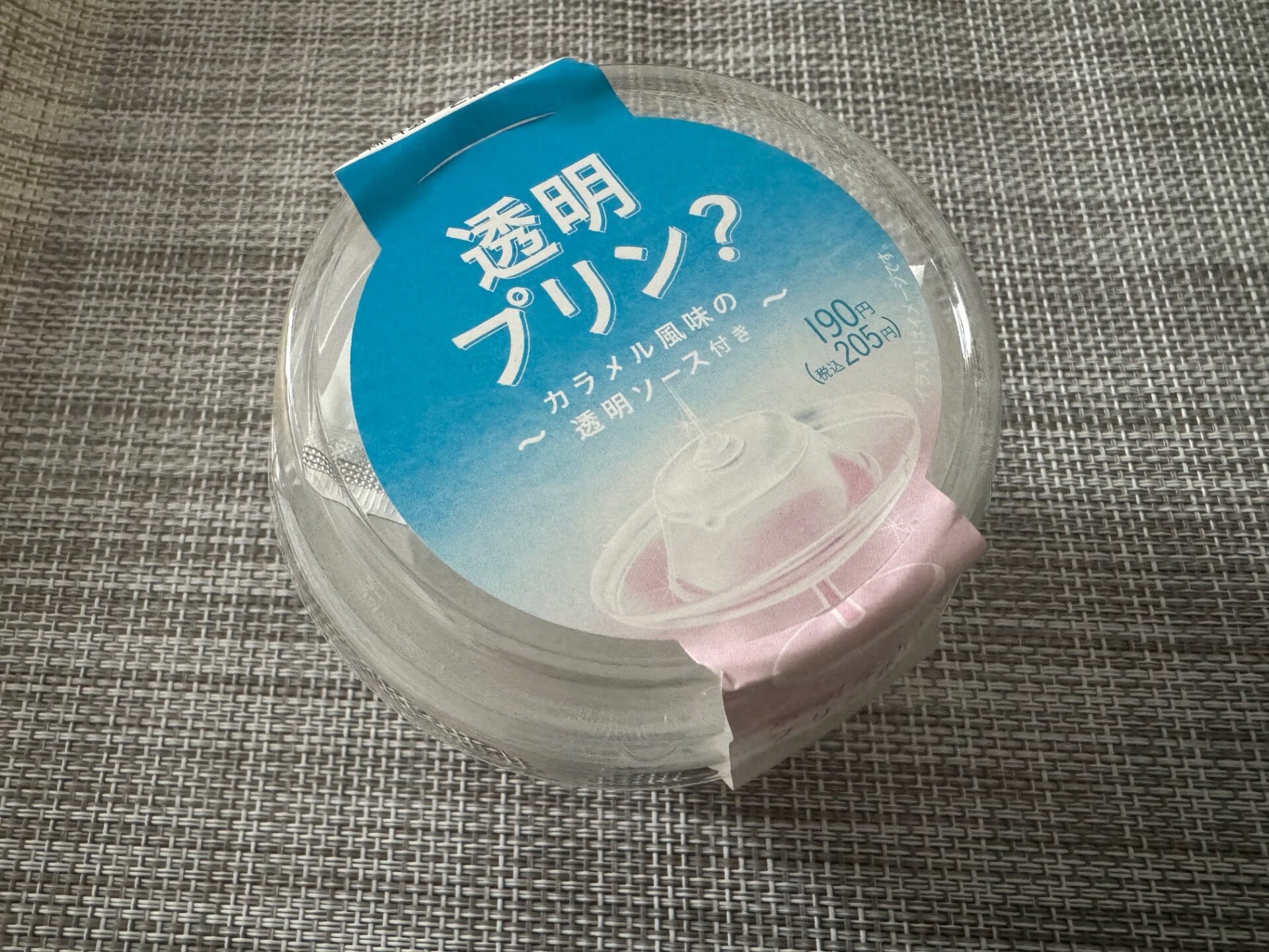 :透明プリンのパッケージの写真。 透明なプリンの容器に、「透明プリン？」とかかれています。パッケージのシールは水色、白、ピンクのグラデーションがかかっていてきれいです