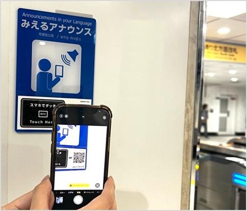 スマートフォンで駅構内に設置された「みえるアナウンス」のQRコードを読み込んでいる写真です